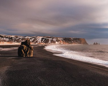 Arnardrangur deniz yığını ve Reynisdrangar bazalt sütunları Güney İzlanda 'da, siyah kumsalda..