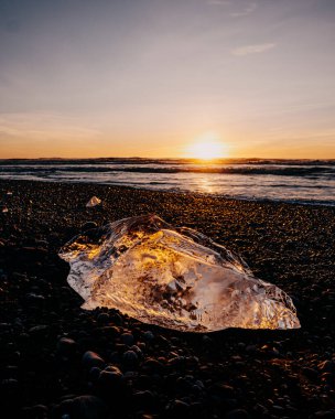 Elmas Sahili 'ndeki buzul buzunu aydınlatan altın gün batımı (Breidamerursandur), Güney İzlanda