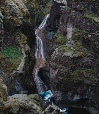 Yosun kaplı Mogafoss şelalesi engebeli uçurumlarda çağlıyor, Güney İzlanda