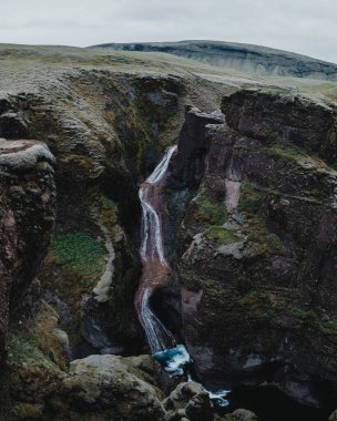 Yosun kaplı Mogafoss şelalesi engebeli uçurumlarda çağlıyor, Güney İzlanda