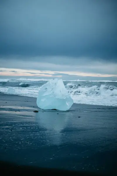 Gündoğumunda Güney İzlanda, Diamond Sahili 'nin siyah kumunda büyük mavi bir buz kütlesi.
