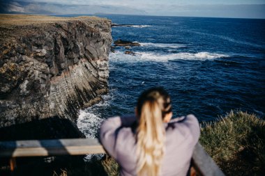 Arnarstapi, Snaefellsnes Yarımadası, Batı İzlanda 'daki okyanus uçurumlarının keyfini çıkaran kadın.