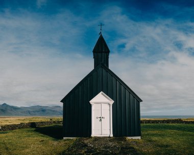 Budirkirkja, Budir, Snaefellsnes Peninsula, Batı İzlanda 'daki ikonik siyah ahşap kilise dramatik bir gökyüzüne ve uzak bir manzaraya karşı kurulmuştur..