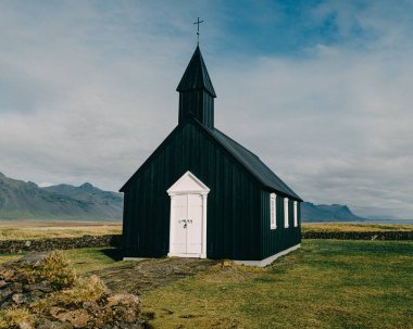 Budirkirkja, Budir, Snaefellsnes Peninsula, Batı İzlanda 'daki ikonik siyah ahşap kilise dramatik bir gökyüzüne ve uzak bir manzaraya karşı kurulmuştur..