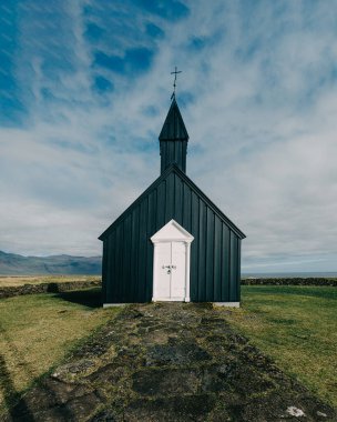 Budirkirkja, Budir, Snaefellsnes Peninsula, Batı İzlanda 'daki ikonik siyah ahşap kilise dramatik bir gökyüzüne ve uzak bir manzaraya karşı kurulmuştur..