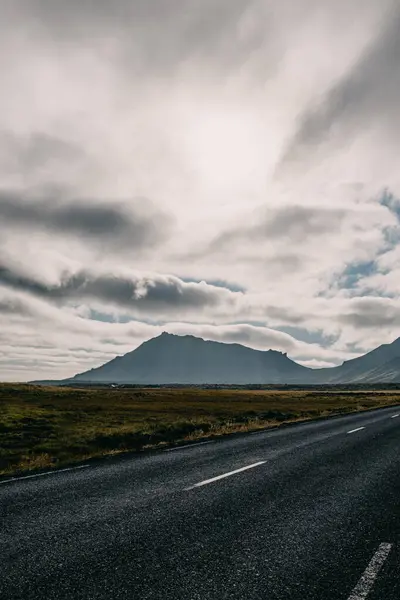 Snaefellsnes Yarımadası, Batı İzlanda 'da karamsar gökyüzünün altında dramatik dağlara çıkan manzara yolu.