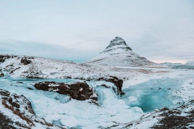 Donmuş Kirkjulsfoss Şelalesi ve kar kaplı Kirkjufell Dağı İzlanda, Snaefellsnes Yarımadası 'nda.