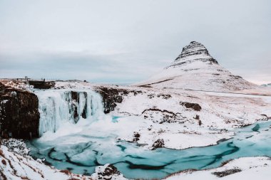 Donmuş Kirkjulsfoss şelalesi ve karla kaplı Kirkjufell dağı, Snaefellsnes Yarımadası, Batı İzlanda