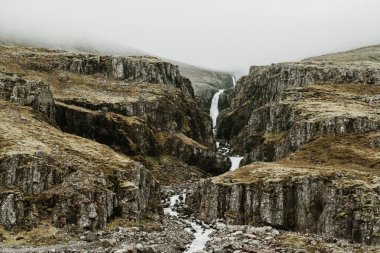 Doğu İzlanda, Reydafjordur 'daki Hrutafoss şelalesinin puslu kanyonu manzarası