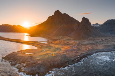 Doğu Icelan 'daki Eystrahorn dağı ve deniz feneri üzerinde altın gün doğumu