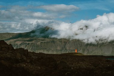 Vattarnes deniz feneri Reydafjordur, İzlanda 'daki sisli kayalıkların altında duruyor.