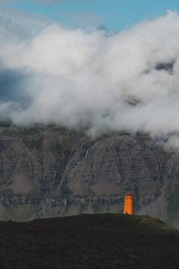 Vattarnes deniz feneri Reydafjordur, İzlanda 'daki sisli kayalıkların altında duruyor.