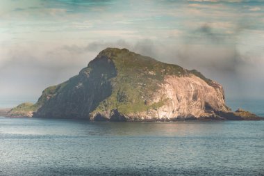 Skrudur Adası, Faşkrudsfjordur, Doğu İzlanda 'daki sakin sulardan yükseliyor.