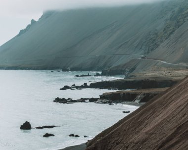Virajlı sahil yolu Fauskasandur, Doğu İzlanda 'nın yukarısındaki sarp kayalıklara sarıldı