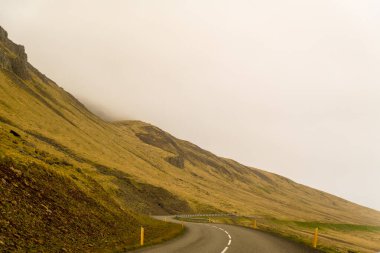 Doğu İzlanda, Stodvarfjordur yakınlarındaki sisli dağlardan geçen kavisli yol