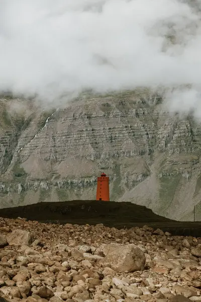 Vattarnes deniz feneri Reydafjordur, İzlanda 'daki sisli kayalıkların altında duruyor.
