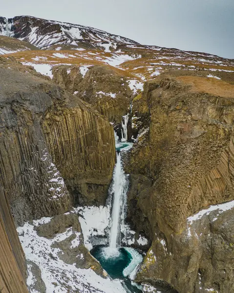 Litlanesfoss şelalesi Doğu İzlanda 'daki bazalt sütunlar ve karlı araziler tarafından çerçevelenmiştir.