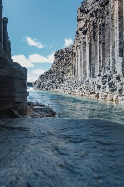 Doğu İzlanda 'daki Studlagil Kanyonu' ndaki buzul nehrinin üzerinden yükselen bazalt kayalıkları