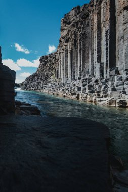 Doğu İzlanda 'daki Studlagil Kanyonu' ndaki buzul nehrinin üzerinden yükselen bazalt kayalıkları