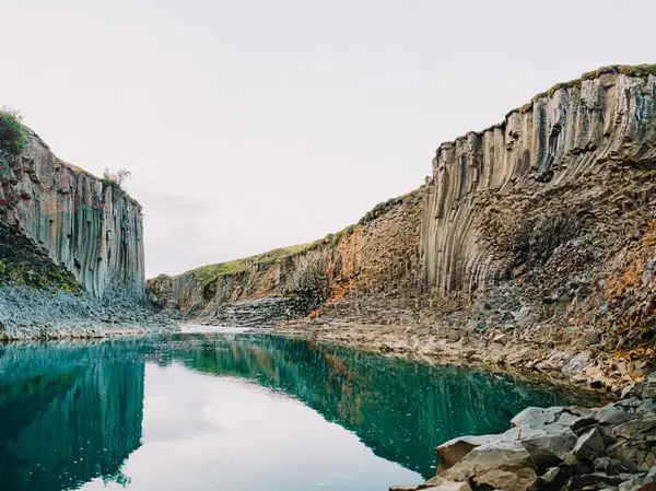 İzlanda, Studlagil Kanyonu 'ndaki turkuaz suya yansıyan canlı bazalt kayalıklar