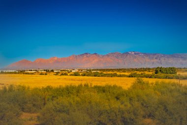 The rugged peaks of the Tucson mountains stand tall under a brilliant Arizona sky, with clouds casting shadows over the desert floor. This stunning landscape is a perfect blend of natural beauty and tranquility clipart