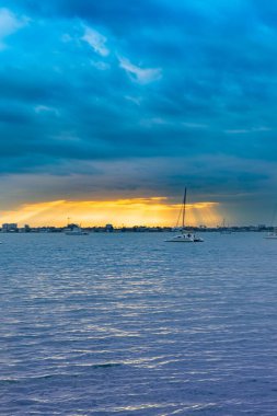 Bayfront Park 'ta sakin bir günbatımının nefes kesen panoramik bir fotoğrafı. Sarasota Florida ABD Ocak 2025' te çekildi. Bu huzurlu görüntü ufkun güzelliğini gökyüzünde harmanlanmış canlı renklerle yakalıyor ve sakin sulara yansıtıyor.