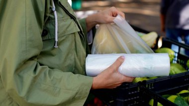 Avrupalı görünümlü genç bir kadının elleri pazarda plastik bir torbayı yırttı.