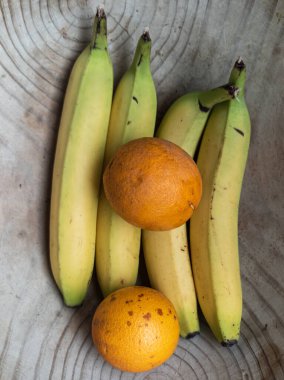 Birkaç muz ve mandalina ahşap bir kasede yatıyor.