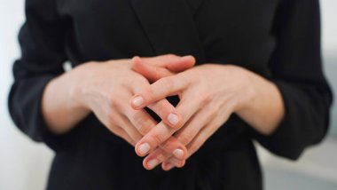 Siyah bir elbisenin arka planında kadın bir masörün elleri. Kozmetik uzmanı. Yakın plan.