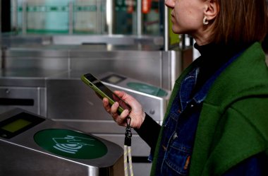 Bir bayan turist Lizbon 'daki tren istasyonunda parasını ödemek için telefonunu kullanıyor.