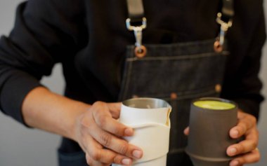 Kahveci matcha hazırlıyor. O, elinde iki fincan tutuyor. - Yakın çekim. Yumuşak odak