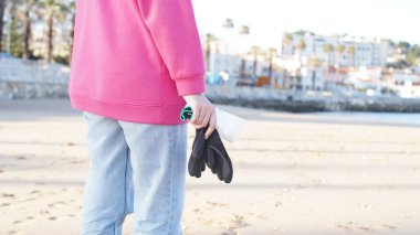 Pembe kazaklı bir kızın elleri temizlik için siyah lastik eldiven tutuyor. Yakın plan