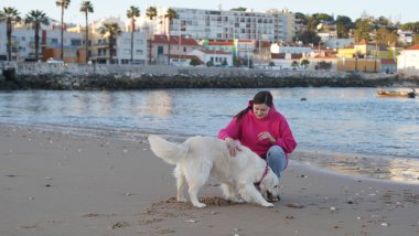 Portekiz 'de okyanus kıyısında köpeğini eğiten bir kız. Yumuşak odak