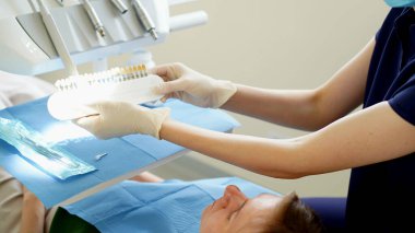 İmplantların rengini doktor seçer. Hasta Avrupalı görünümlü genç bir kadın. Yumuşak odaklanma. Yakın plan