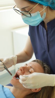 Doktor dişleri için implantların rengini seçerken hasta elinde tuttuğu aynaya bakar. Yumuşak odaklanma. Yakın plan