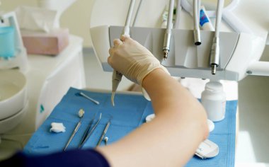 Diş hekiminin elindeki tek kullanımlık lastik eldivenlerde diş tedavisi için metal aletler bulunur. - Yakın çekim. Yumuşak odak