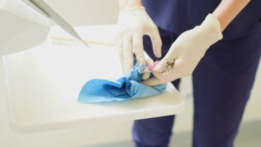 Diş hekiminin elleri kullan-at lastik eldivenlerle dişçi muayenesinden sonra kullanılmış malzeme topluyor. Yumuşak odaklanma. Yakın plan