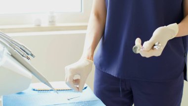 Diş hekiminin elindeki tek kullanımlık lastik eldivenlerde diş tedavisi için metal aletler bulunur. - Yakın çekim. Yumuşak odak