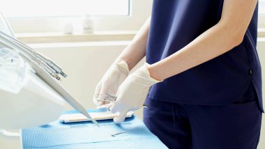 Diş hekiminin elindeki tek kullanımlık lastik eldivenlerde diş tedavisi için metal aletler bulunur. - Yakın çekim. Yumuşak odak