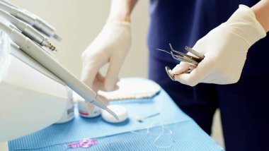 Diş hekiminin elindeki tek kullanımlık lastik eldivenlerde diş tedavisi için metal aletler bulunur. - Yakın çekim. Yumuşak odak