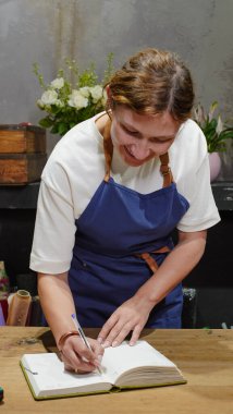 Dişi bir çiçekçi not defterine not alıyor. Yakın plan. Küçük işletme.