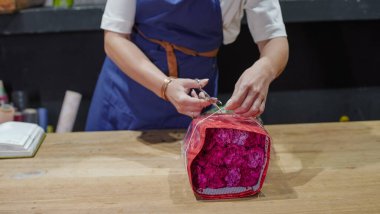 Çiçekçi bir paket gül açıyor. Küçük bir iş. Yakın plan. Yumuşak odak.