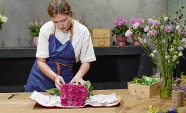 Çiçekçi bir paket gül açıyor. Küçük bir iş. Yakın plan. Yumuşak odak.
