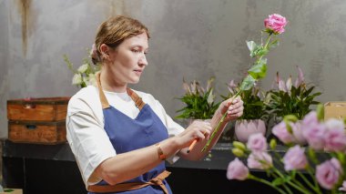 Bir çiçekçi çiçekçide pembe güllerden bir buket yapar. Küçük bir iş. Yakın plan.