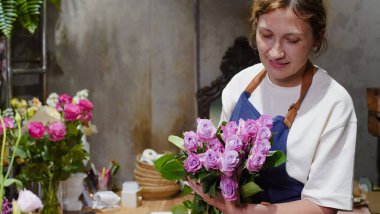 Çiçekçi bir paket gül açıyor. Küçük bir iş. Yakın plan. Yumuşak odak.