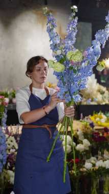 Çiçekçide bir çiçekçi mavi desenlerden bir buket yapar. Küçük bir iş. Yakın plan. Yumuşak odak.