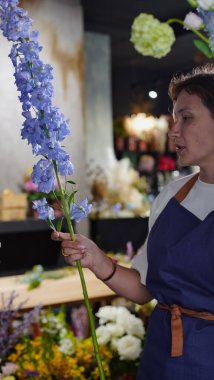 Çiçekçide bir çiçekçi mavi desenlerden bir buket yapar. Küçük bir iş. Yakın plan. Yumuşak odak.