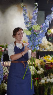 Çiçekçide bir çiçekçi mavi desenlerden bir buket yapar. Küçük bir iş. Yakın plan. Yumuşak odak.