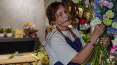 Çiçekçide bir çiçekçi mavi desenlerden bir buket yapar. Küçük bir iş. Yakın plan. Yumuşak odak.