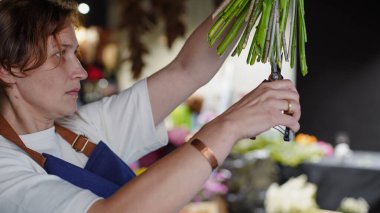 Çiçekçide bir çiçekçi mavi desenlerden bir buket yapar. Küçük bir iş. Yakın plan. Yumuşak odaklanma. Çiçekçi çiçekleri budarmış..